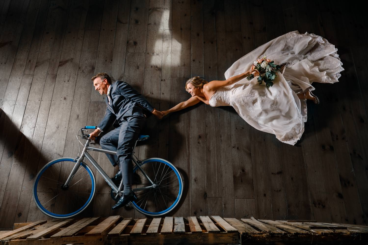 Bride flies behind groom on bike at a barn wedding in vermont