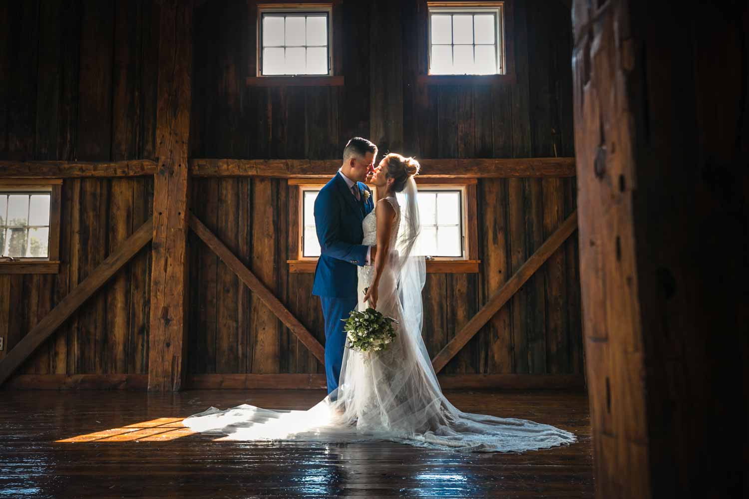 bride and groom embrace in a barn at a vermont wedding